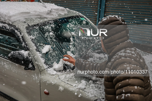 A man is clearing snow from his car in Baramulla, Jammu and Kashmir, India, on February 20, 2024. 