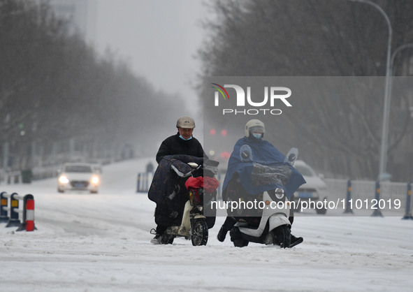 Citizens are riding in the snow on a street in Fuyang, China, on February 21, 2024. 