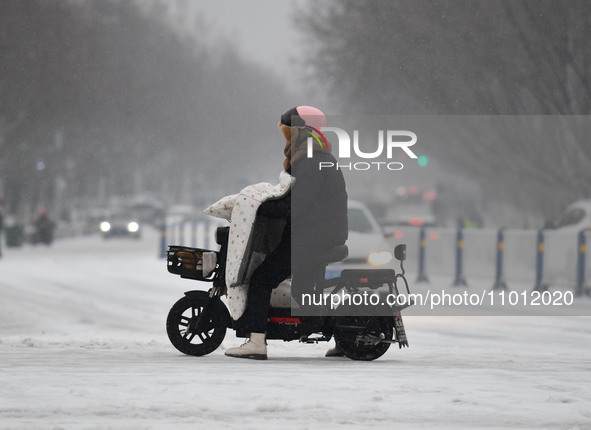 Citizens are riding in the snow on a street in Fuyang, China, on February 21, 2024. 