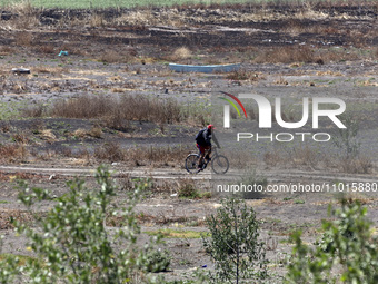 A person is riding a bicycle next to Zumpango Lagoon, which is affected by drought due to the lack of rain, in Zumpango de Ocampo, Mexico, o...