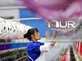 A female worker is merging silk at a production workshop of a silk company in Chongqing, China, on February 23, 2024. (