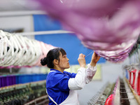 A female worker is merging silk at a production workshop of a silk company in Chongqing, China, on February 23, 2024. (