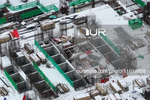 Workers are working at a building construction site as snow is falling in Nanjing, China, on February 24, 2024. 