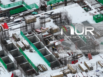 Workers are working at a building construction site as snow is falling in Nanjing, China, on February 24, 2024. (