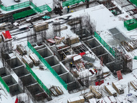 Workers are working at a building construction site as snow is falling in Nanjing, China, on February 24, 2024. (