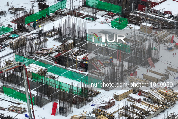 Workers are working at a building construction site as snow is falling in Nanjing, China, on February 24, 2024. 