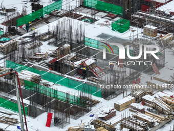 Workers are working at a building construction site as snow is falling in Nanjing, China, on February 24, 2024. (