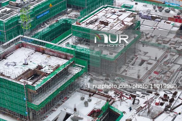 Workers are working at a building construction site as snow is falling in Nanjing, China, on February 24, 2024. 