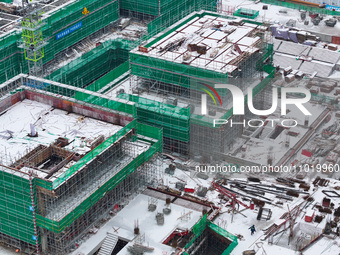 Workers are working at a building construction site as snow is falling in Nanjing, China, on February 24, 2024. (