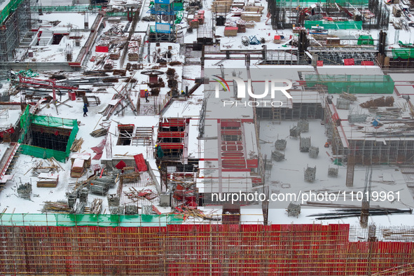 Workers are working at a building construction site as snow is falling in Nanjing, China, on February 24, 2024. 