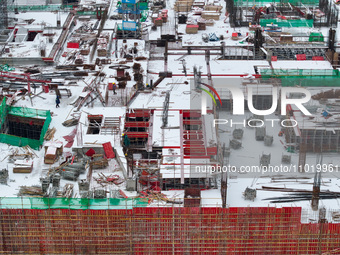 Workers are working at a building construction site as snow is falling in Nanjing, China, on February 24, 2024. (