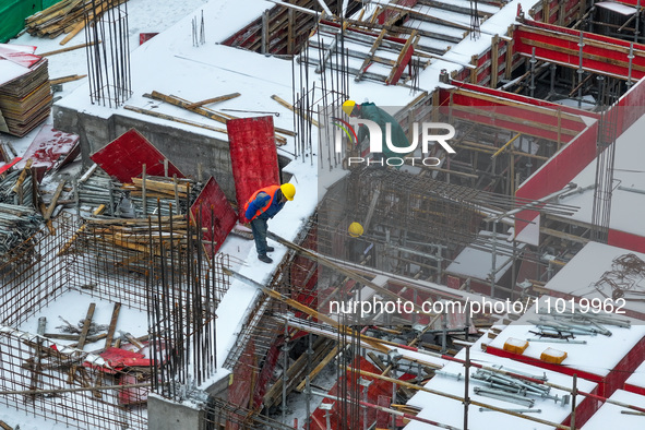 Workers are working at a building construction site as snow is falling in Nanjing, China, on February 24, 2024. 