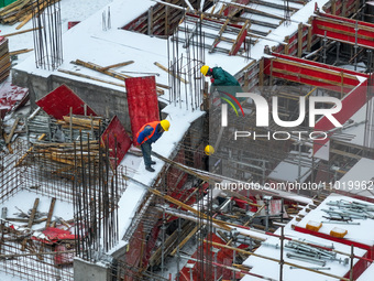 Workers are working at a building construction site as snow is falling in Nanjing, China, on February 24, 2024. (