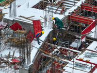 Workers are working at a building construction site as snow is falling in Nanjing, China, on February 24, 2024. (