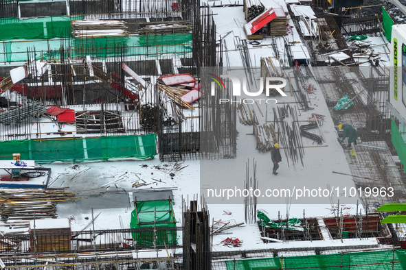 Workers are working at a building construction site as snow is falling in Nanjing, China, on February 24, 2024. 