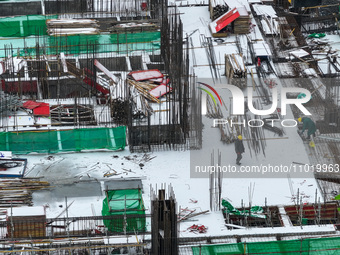 Workers are working at a building construction site as snow is falling in Nanjing, China, on February 24, 2024. (