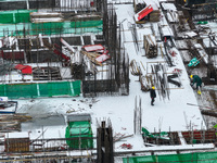 Workers are working at a building construction site as snow is falling in Nanjing, China, on February 24, 2024. (