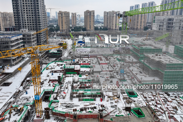 Workers are working at a building construction site as snow is falling in Nanjing, China, on February 24, 2024. 