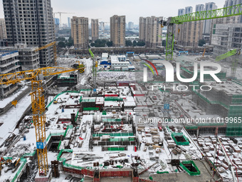 Workers are working at a building construction site as snow is falling in Nanjing, China, on February 24, 2024. (