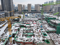 Workers are working at a building construction site as snow is falling in Nanjing, China, on February 24, 2024. (