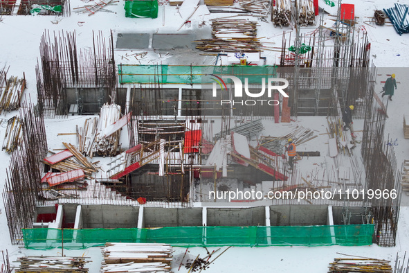 Workers are working at a building construction site as snow is falling in Nanjing, China, on February 24, 2024. 