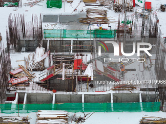 Workers are working at a building construction site as snow is falling in Nanjing, China, on February 24, 2024. (