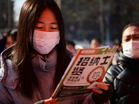 Job seekers are learning about job openings at a booth of an employment company at a spring job fair for SMEs in Liaocheng, China, on Februa...