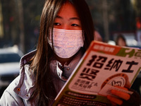 Job seekers are learning about job openings at a booth of an employment company at a spring job fair for SMEs in Liaocheng, China, on Februa...