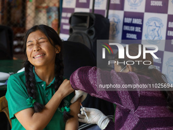 A Nepali student is reacting as a paramedic administers a vaccine against measles-rubella at a local school in Kathmandu, Nepal, on February...