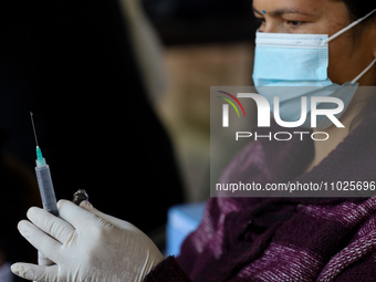 A Nepali paramedic is preparing a dose of the anti-measles-rubella vaccine as she gets ready to administer it during the nationwide vaccinat...