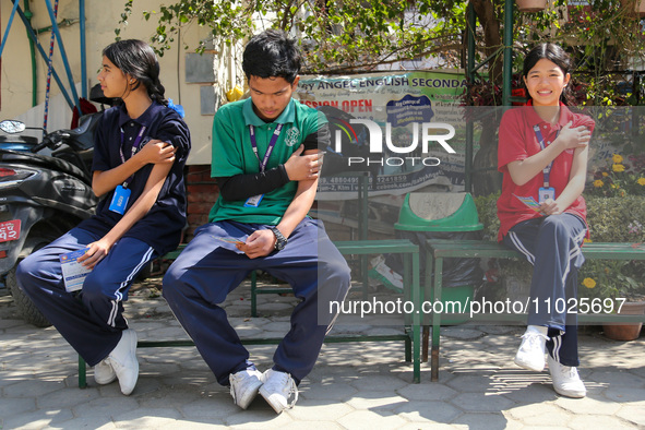 Nepali students are sitting on a bench after being administered vaccines against measles and rubella in Kathmandu, Nepal, on February 25, 20...