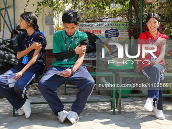 Nepali students are sitting on a bench after being administered vaccines against measles and rubella in Kathmandu, Nepal, on February 25, 20...