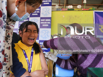 A Nepali student is reacting as a paramedic administers a vaccine against measles-rubella at a local school in Kathmandu, Nepal, on February...