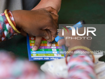 A Nepali health official is marking the nail of a vaccinated student at a vaccination center after administering the anti-measles-rubella va...