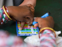 A Nepali health official is marking the nail of a vaccinated student at a vaccination center after administering the anti-measles-rubella va...