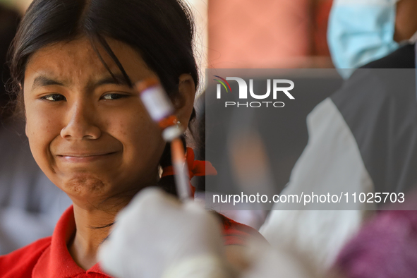 A Nepali student is reacting as a paramedic prepares to administer a vaccine against measles-rubella at a local school in Kathmandu, Nepal,...