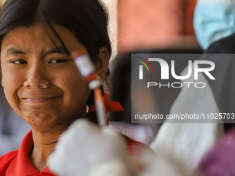 A Nepali student is reacting as a paramedic prepares to administer a vaccine against measles-rubella at a local school in Kathmandu, Nepal,...