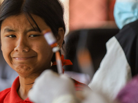 A Nepali student is reacting as a paramedic prepares to administer a vaccine against measles-rubella at a local school in Kathmandu, Nepal,...