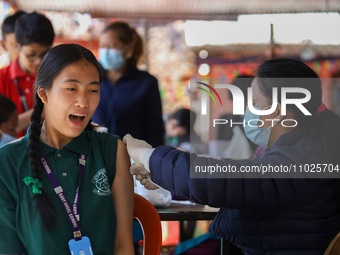 A Nepali student is reacting as a paramedic administers a vaccine against measles-rubella at a local school in Kathmandu, Nepal, on February...