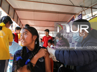 A Nepali student is reacting as a paramedic administers a vaccine against measles-rubella at a local school in Kathmandu, Nepal, on February...