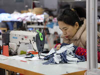 A worker is producing children's clothing products at a workshop of a children's clothing manufacturer in Binzhou, China, on February 26, 20...