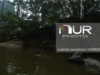 Plastic waste scavengers are collecting debris in the Babura River, which is polluted by plastic waste, in Medan, North Sumatra, Indonesia,...