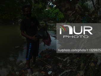 Plastic waste scavengers are collecting debris in the Babura River, which is polluted by plastic waste, in Medan, North Sumatra, Indonesia,...