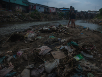 Two teenage girls are posing with their cellphones in the Deli River, which is polluted by plastic waste, in Medan, North Sumatra, Indonesia...