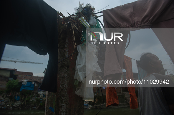 A resident is standing on the banks of the Deli River, which is polluted with plastic waste following floods, in Medan, North Sumatra, Indon...