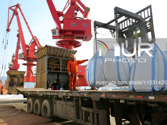 Dock workers are loading fertilizer that has been unloaded from a cargo ship at the port of Lianyungang, in Jiangsu Province, China, on Febr...