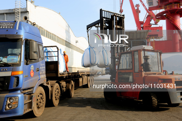 Dock workers are loading fertilizer that has been unloaded from a cargo ship at the port of Lianyungang, in Jiangsu Province, China, on Febr...