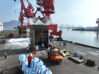 Dock workers are loading fertilizer that has been unloaded from a cargo ship at the port of Lianyungang, in Jiangsu Province, China, on Febr...