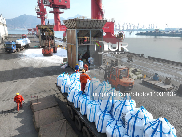 Dock workers are loading fertilizer that has been unloaded from a cargo ship at the port of Lianyungang, in Jiangsu Province, China, on Febr...