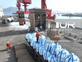 Dock workers are loading fertilizer that has been unloaded from a cargo ship at the port of Lianyungang, in Jiangsu Province, China, on Febr...